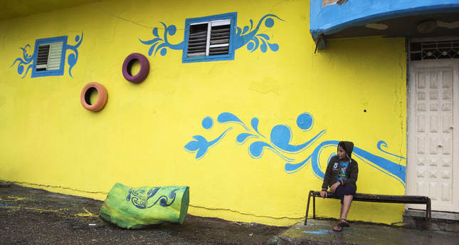 A Palestinian boy sits outside his family house that was painted by Palestinian artists in the al-Shati Refugee Camp in Gaza City, Tuesday, Nov. 17, 2015. More than 30 artists took part in the "Gaza More Beautiful" project funded by Padico Holding, a leading investment and development company in the Palestinian Territories. (AP Photo/Adel Hana)